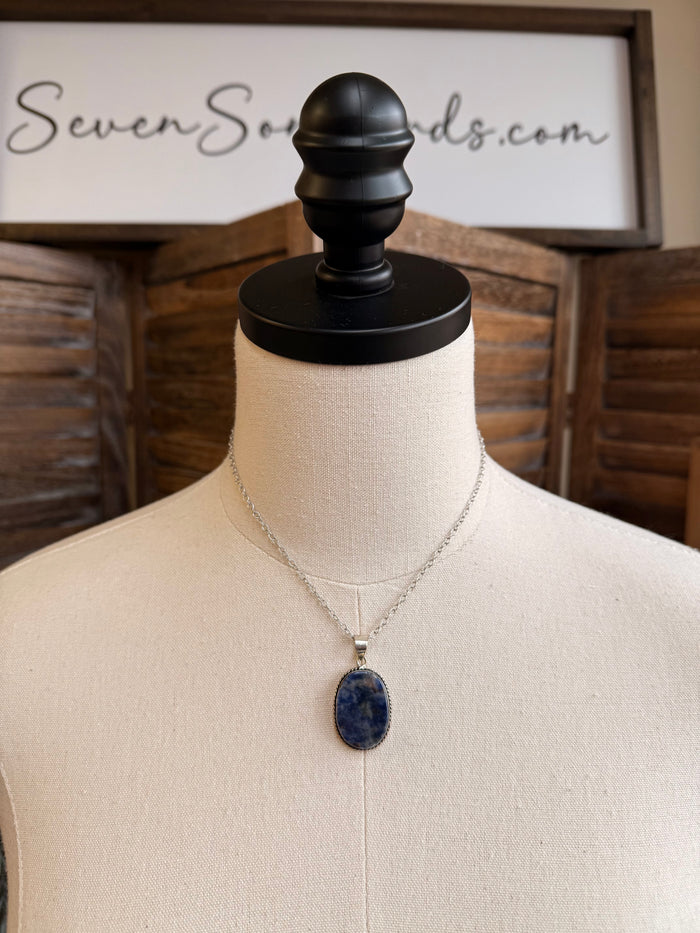 Layered silver-plated necklace with oval blue sodalite pendant on a display mannequin