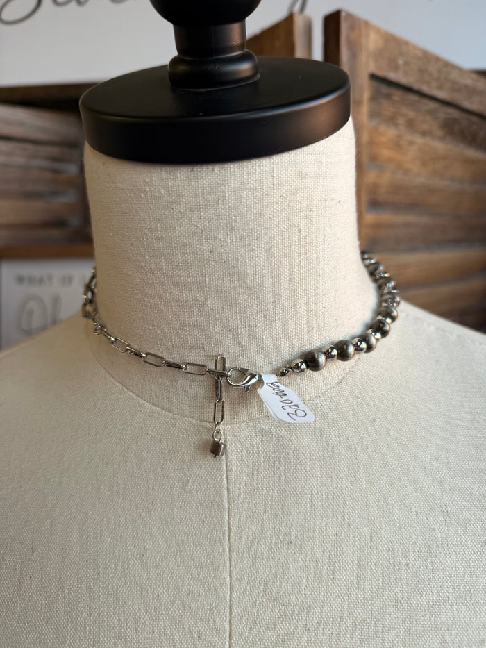 Silver pearl chain necklace with cross charm and small tag on mannequin