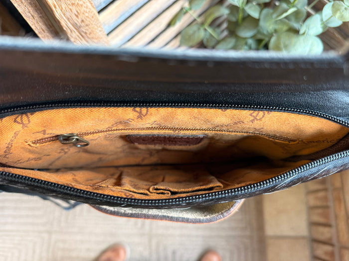 Open cowhide crossbody clutch interior with tan lining and black zipper