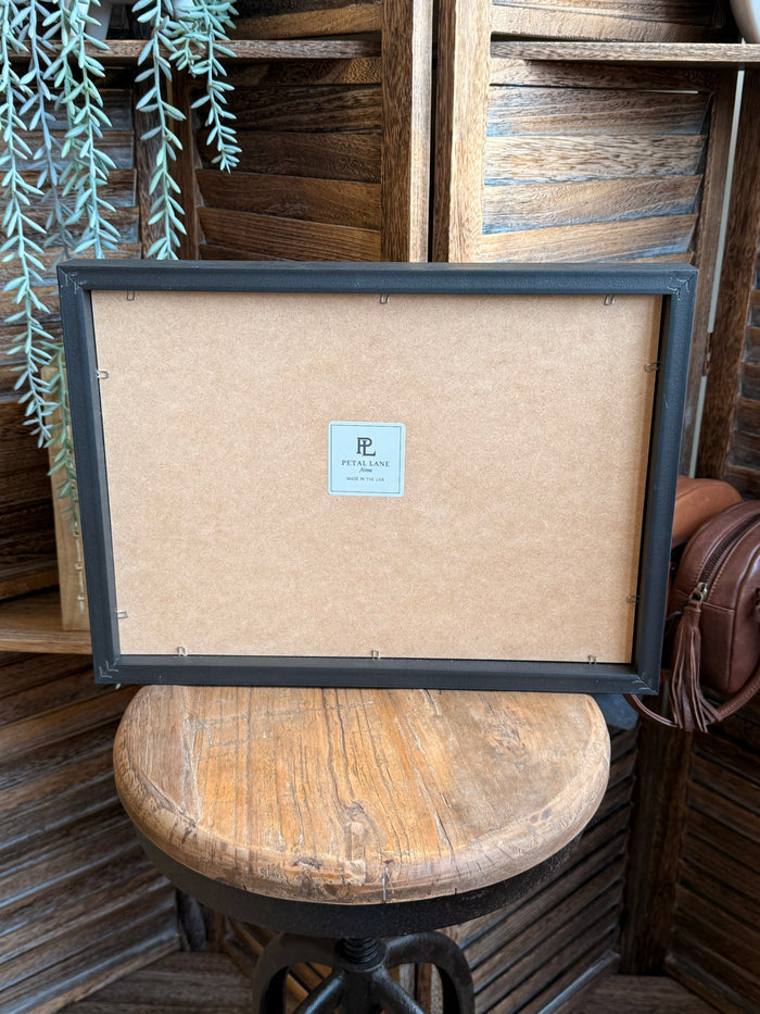 Back of framed artwork with kraft paper backing and small maker label, dark frame
