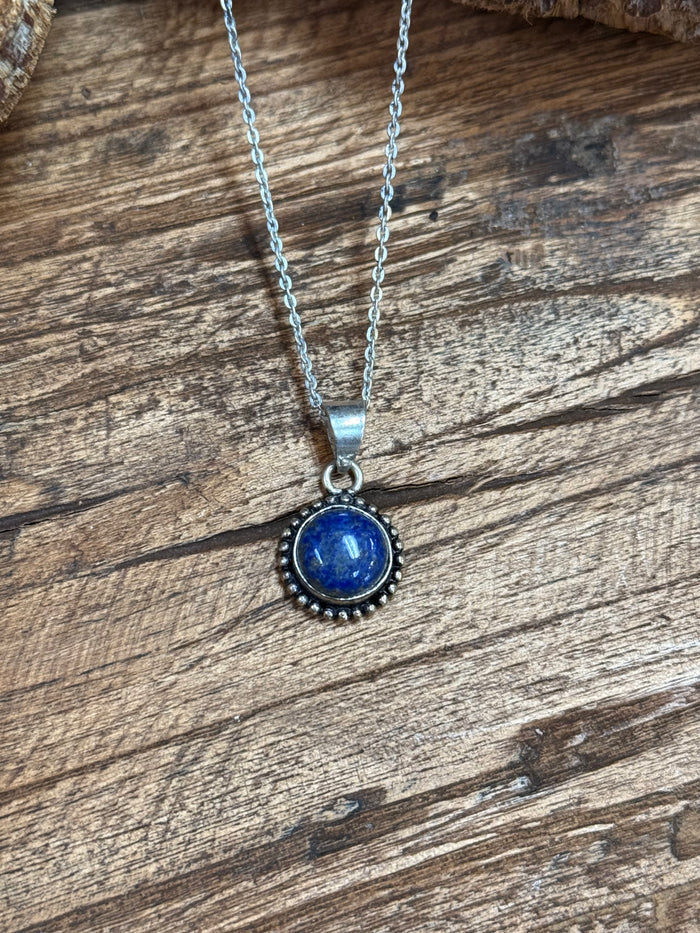 Silver-plated necklace pendant with blue round cabochon in textured bezel