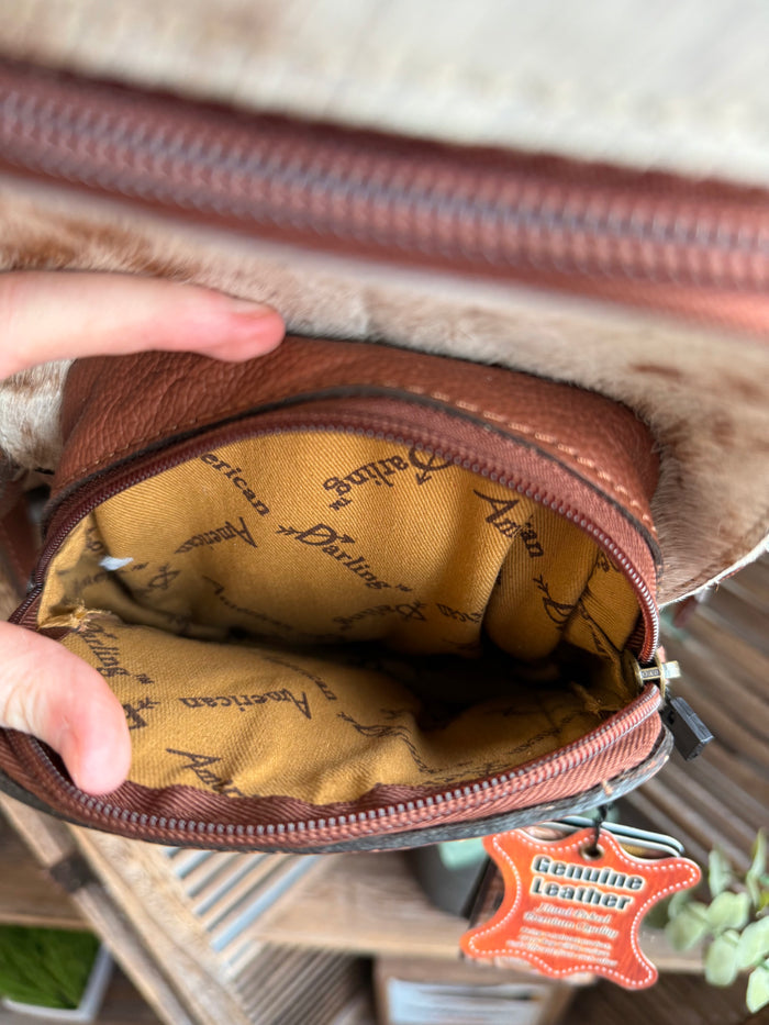 Inside hair-on sling backpack with tan logo-pattern lining and zipper pocket