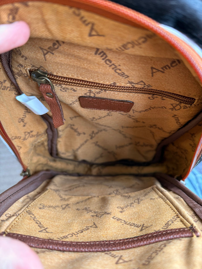 Interior of leather sling bag with tan patterned lining and zipper pocket