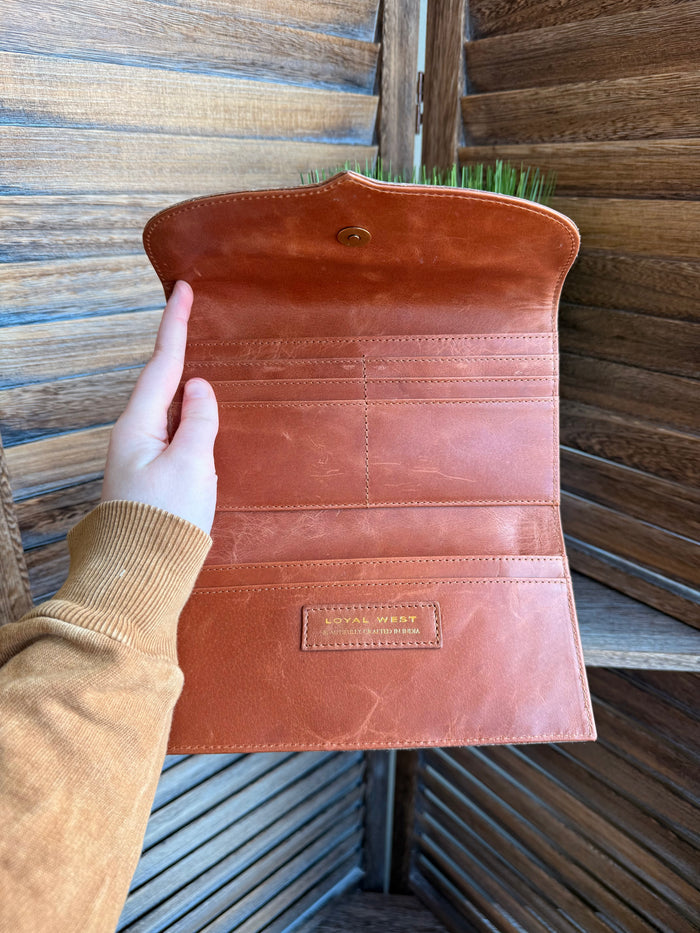 Brown leather flap wallet open with card slots, stitched seams, and small logo patch.
