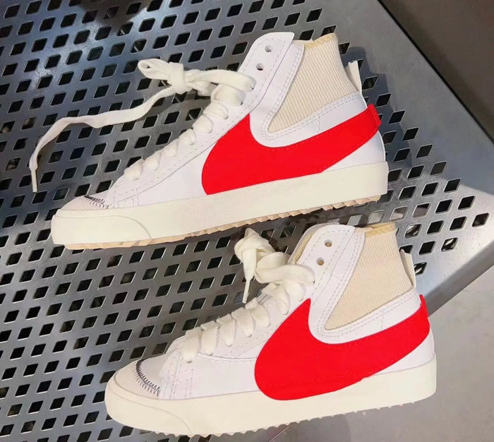 Two high-top sneakers with white uppers, beige ankle panels, red Nike swooshes