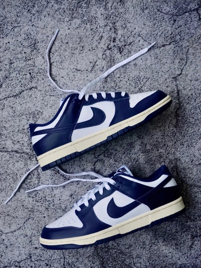 Pair of low-top sneakers with white laces, navy uppers, and cream soles