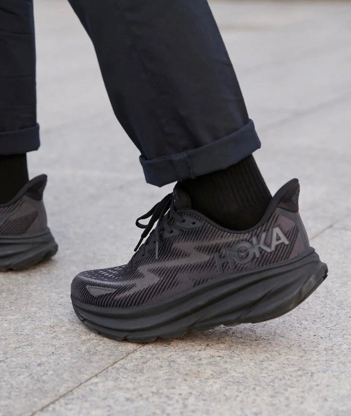 Hoka Clifton 9 Wide dark shoe worn with black socks and treaded outsole