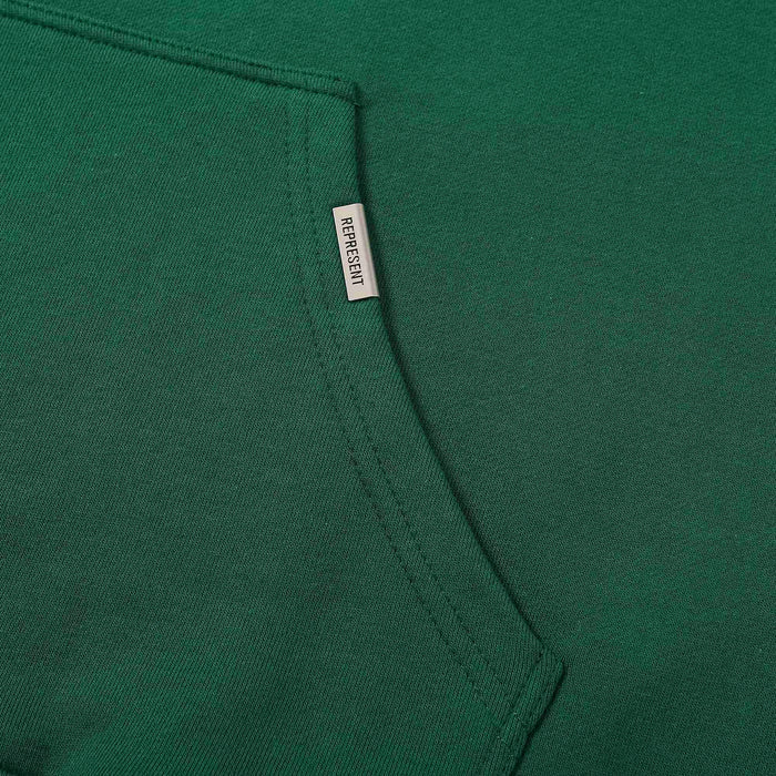 Green hoodie side seam with small brand label tag