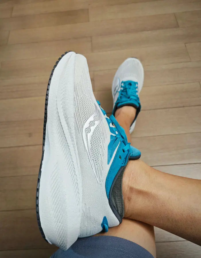 Teal running shoes on feet with light gray cushioned sole and breathable upper