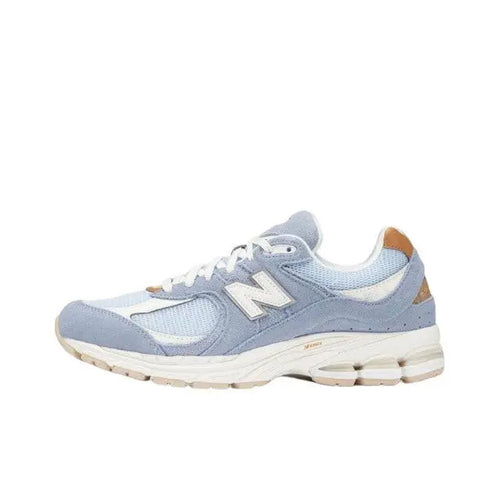 New Balance 2002R sneaker in light blue with white laces, tan heel, and off-white sole
