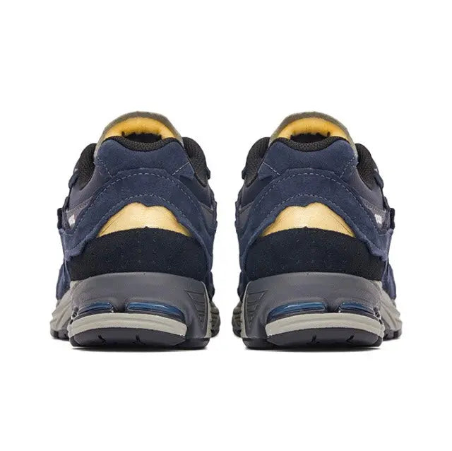 Back view of navy New Balance 2002R sneakers with yellow heel lining and air sole