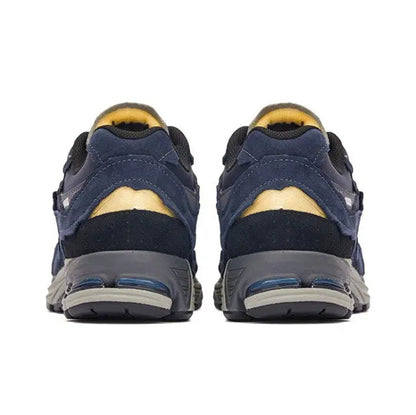 Back view of navy New Balance 2002R sneakers with yellow heel lining and air sole