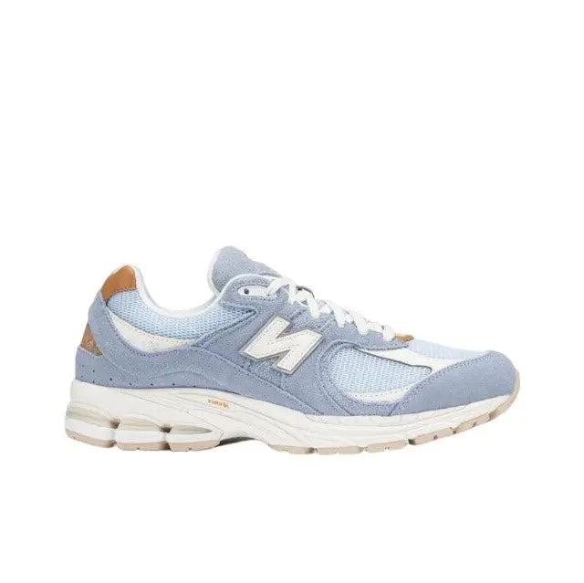 New Balance sneaker in light blue with white laces, tan side hits, and chunky off-white sole