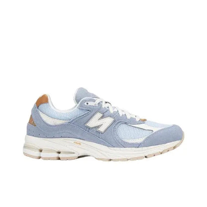 New Balance sneaker in light blue with white laces, tan side hits, and chunky off-white sole