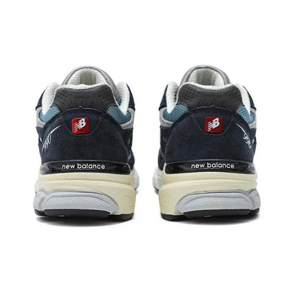 New Balance 990 sneakers, rear view with dark navy heel and light blue trim.