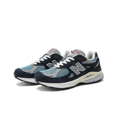 New Balance 990 sneakers, angled front view in dark navy with light blue mesh.