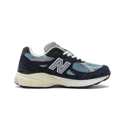 New Balance 990 sneakers, side view in dark navy and light blue with white midsoles.
