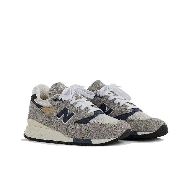 Grey sneaker with blue detailing and tan patch, lace-up style, low-profile runner
