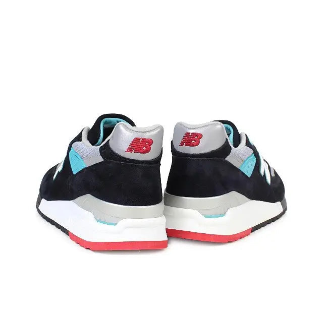 New Balance 998 sneakers heel view, black suede with teal panels, white midsole, red stripe