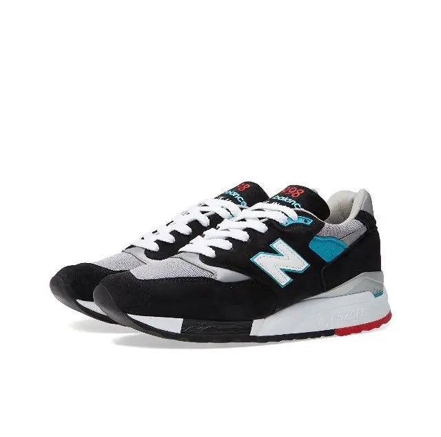 New Balance 998 sneakers side view, gray and black upper with teal N logo, red heel detail