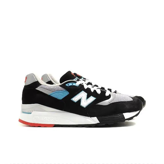 New Balance 998 sneakers front side, white laces on black upper with teal panel, red trim