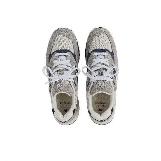 Pair of grey sneakers with white laces and blue details, NB logo on uppers