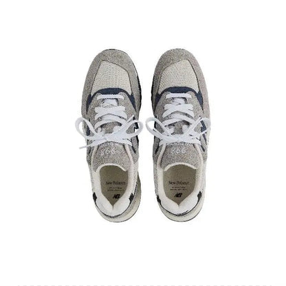 Pair of grey sneakers with white laces and blue details, NB logo on uppers