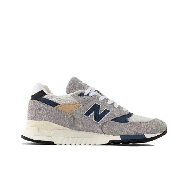 Grey sneaker with blue accents and tan patch, low-profile runner with lace-up upper