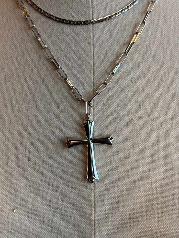 Silver-tone cross pendant on a layered curb chain necklace