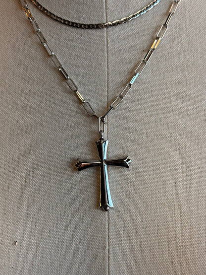 Silver-tone cross pendant on a layered curb chain necklace