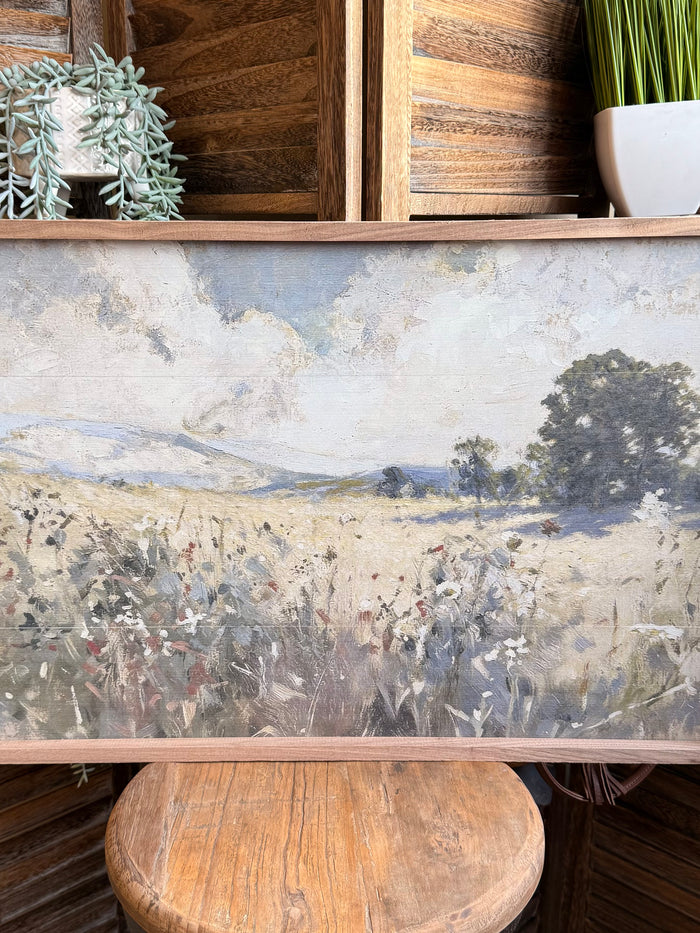 Close-up of framed prairie landscape print with flowers, hills, and trees