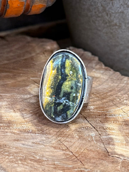 Silver-plated adjustable ring with oval yellow-green cabochon, textured bezel edges