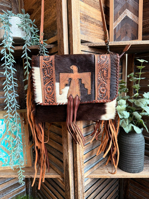 Fringed cowhide crossbody purse with tooled leather cross detail and long brown tassels