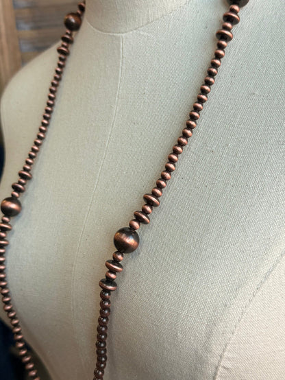 Close-up of mixed copper pearl beads on a long strand necklace