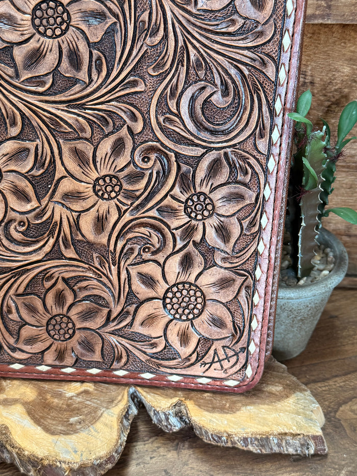 Hand-tooled leather folio notebook close-up of floral toolwork border and edge stitching