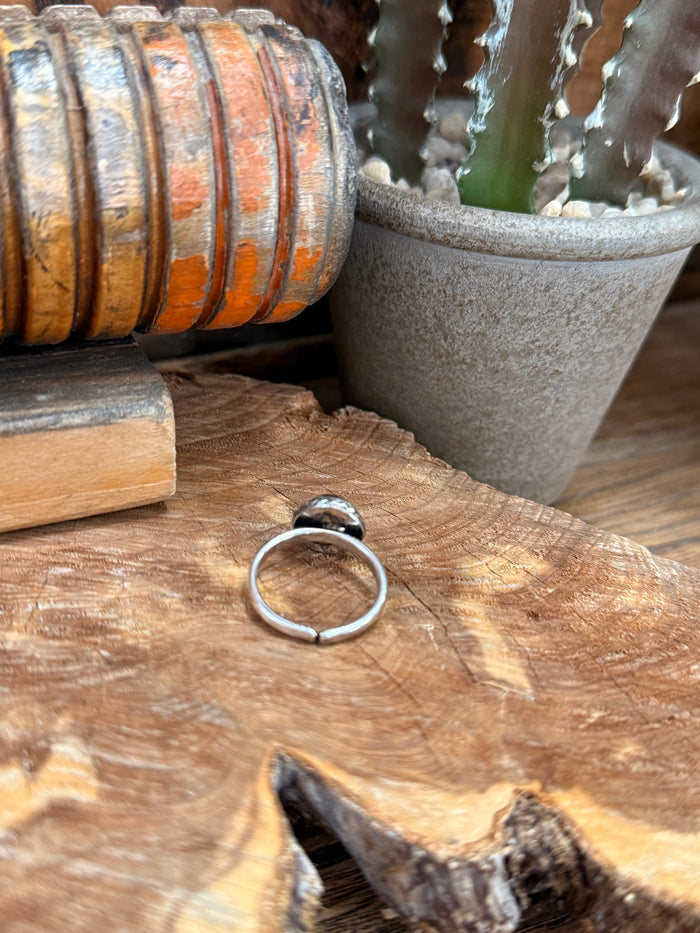 Silver adjustable ring band with round red stone inset, side view