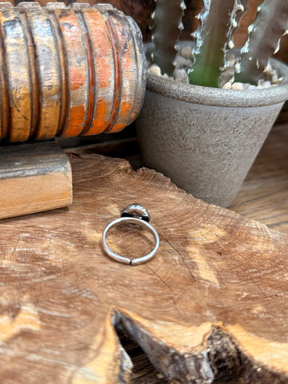 Silver adjustable ring band with round red stone inset, side view