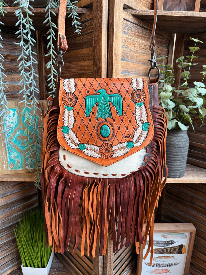 Fringed cowhide crossbody purse with turquoise Thunderbird motif and patterned flap