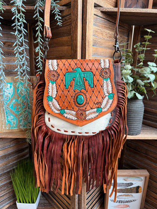Fringed cowhide crossbody purse with turquoise Thunderbird motif and patterned flap