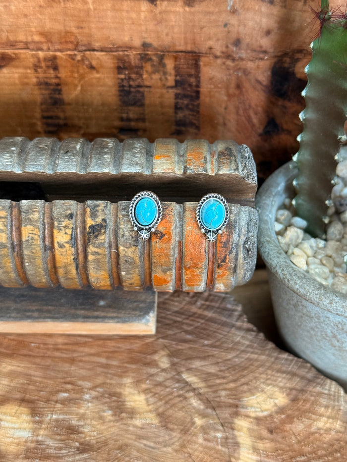 Silver oval turquoise stud earrings with ornate bezel and small starburst dangles