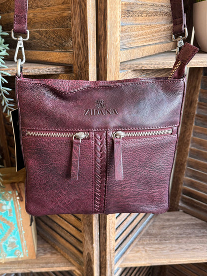 Plum leather crossbody bag with double front pockets, zip closures, and logo detail