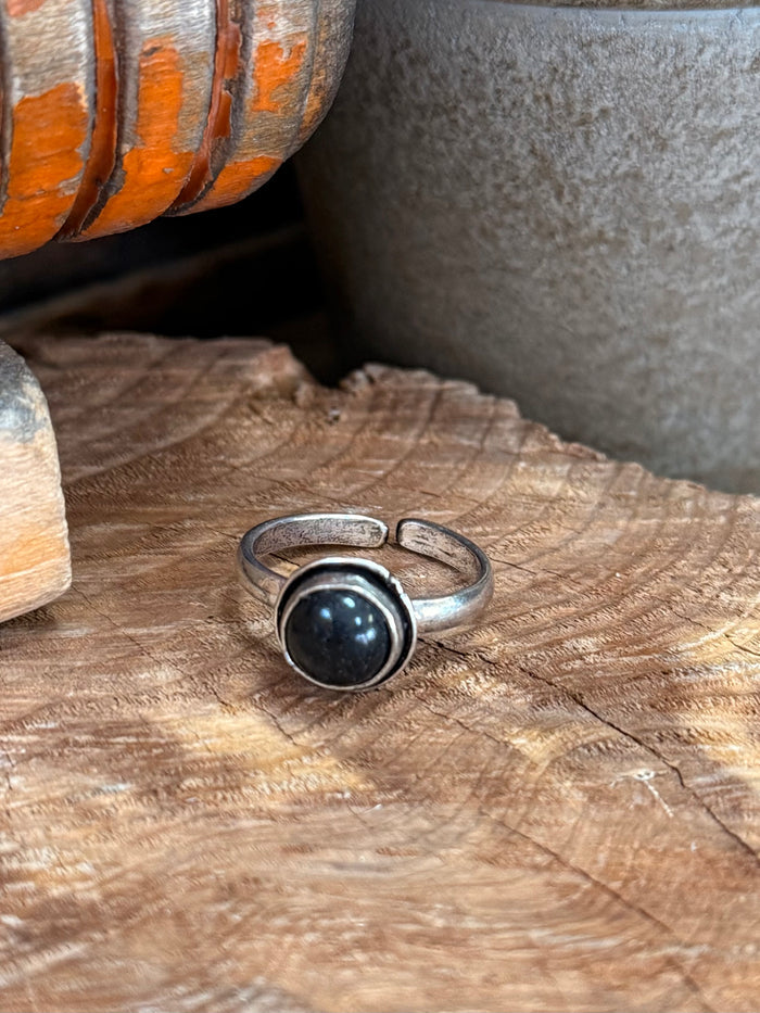 Adjustable silver-toned ring with round dark stone cabochon and bezel setting