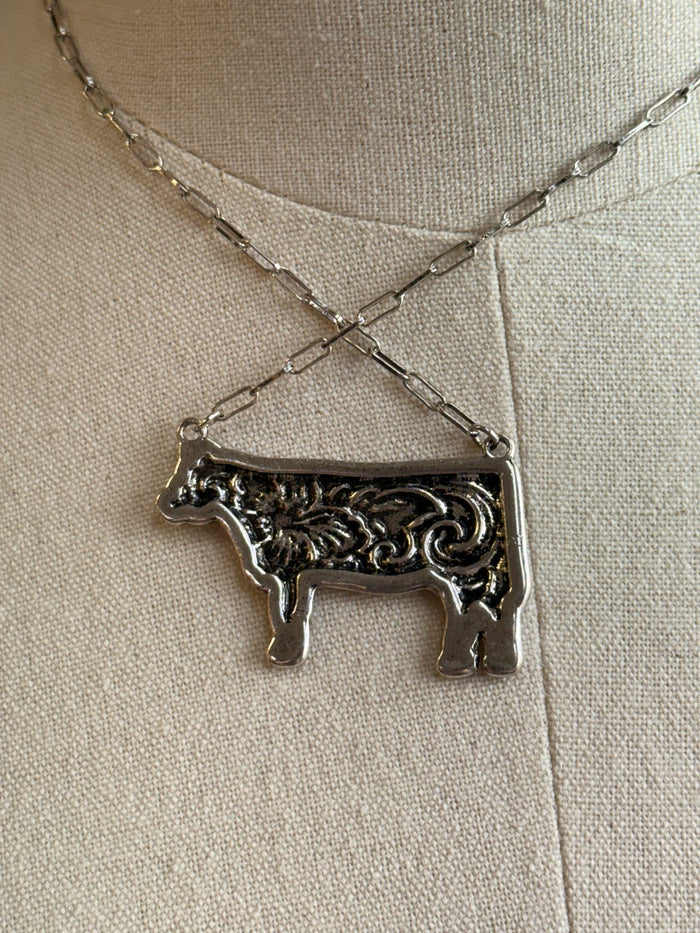 Silver-tone engraved cow pendant necklace close-up with twisted chain links