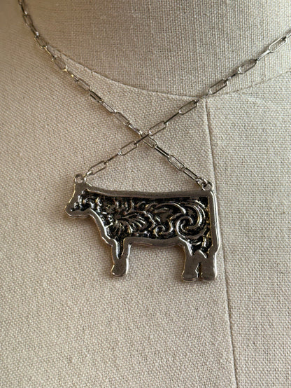 Silver-tone engraved cow pendant necklace close-up with twisted chain links