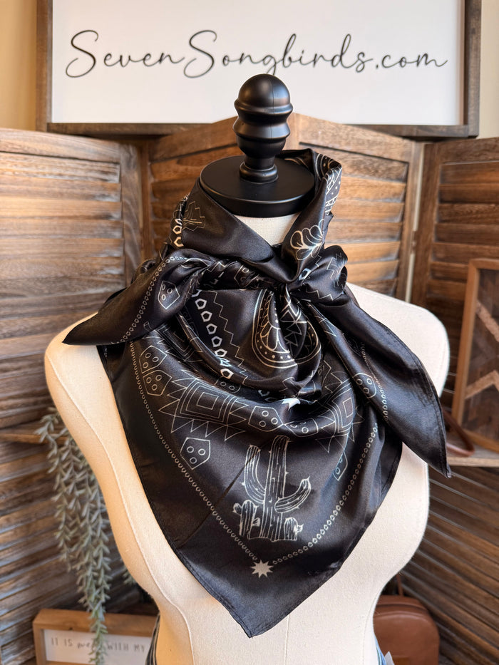 Black wild rag scarf with white paisley print, tied in a knot on a mannequin