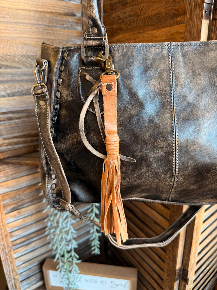 Leather tote with an orange leather tassel clip and braided hanging fringe