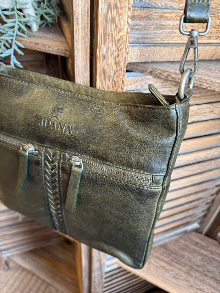 Olive leather crossbody bag angled view with braided center zipper and left side pocket.