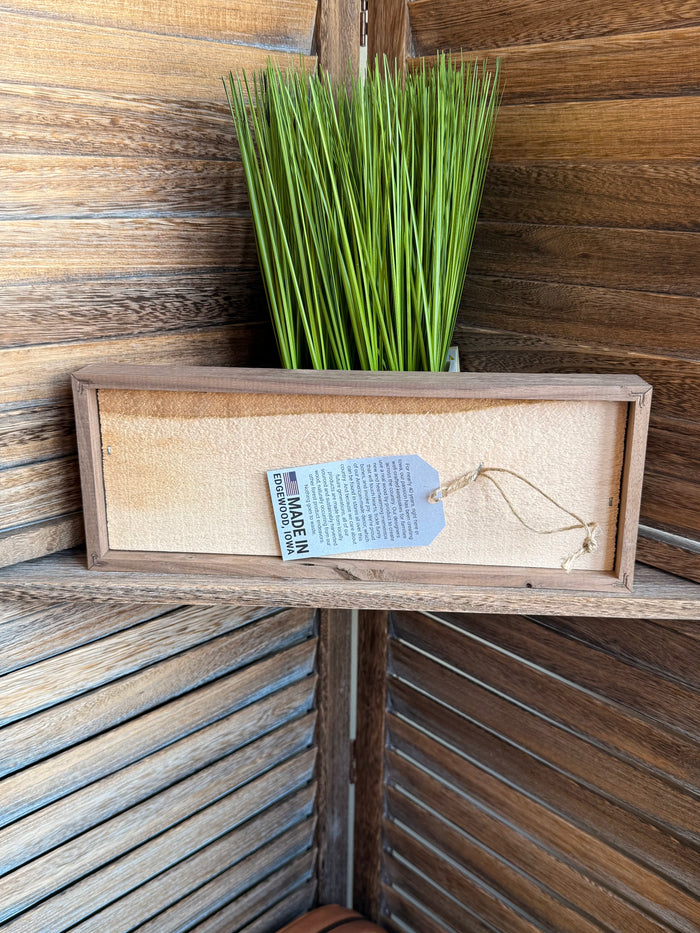 Back of framed 12x4 artwork with hanging cord and small label on light panel