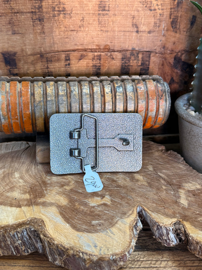 Rectangle belt buckle backplate in textured blue metal with prong and small hanging tag