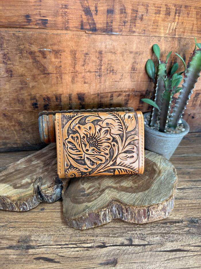 Tan leather bifold wallet with carved floral pattern and snap front